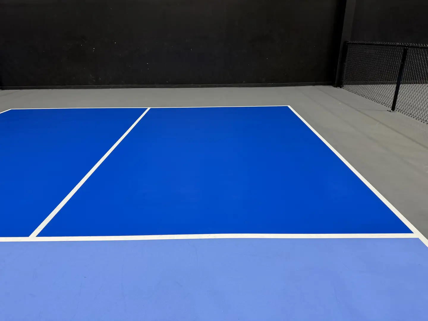 Indoor pickleball court with blue playing surface and white lines.