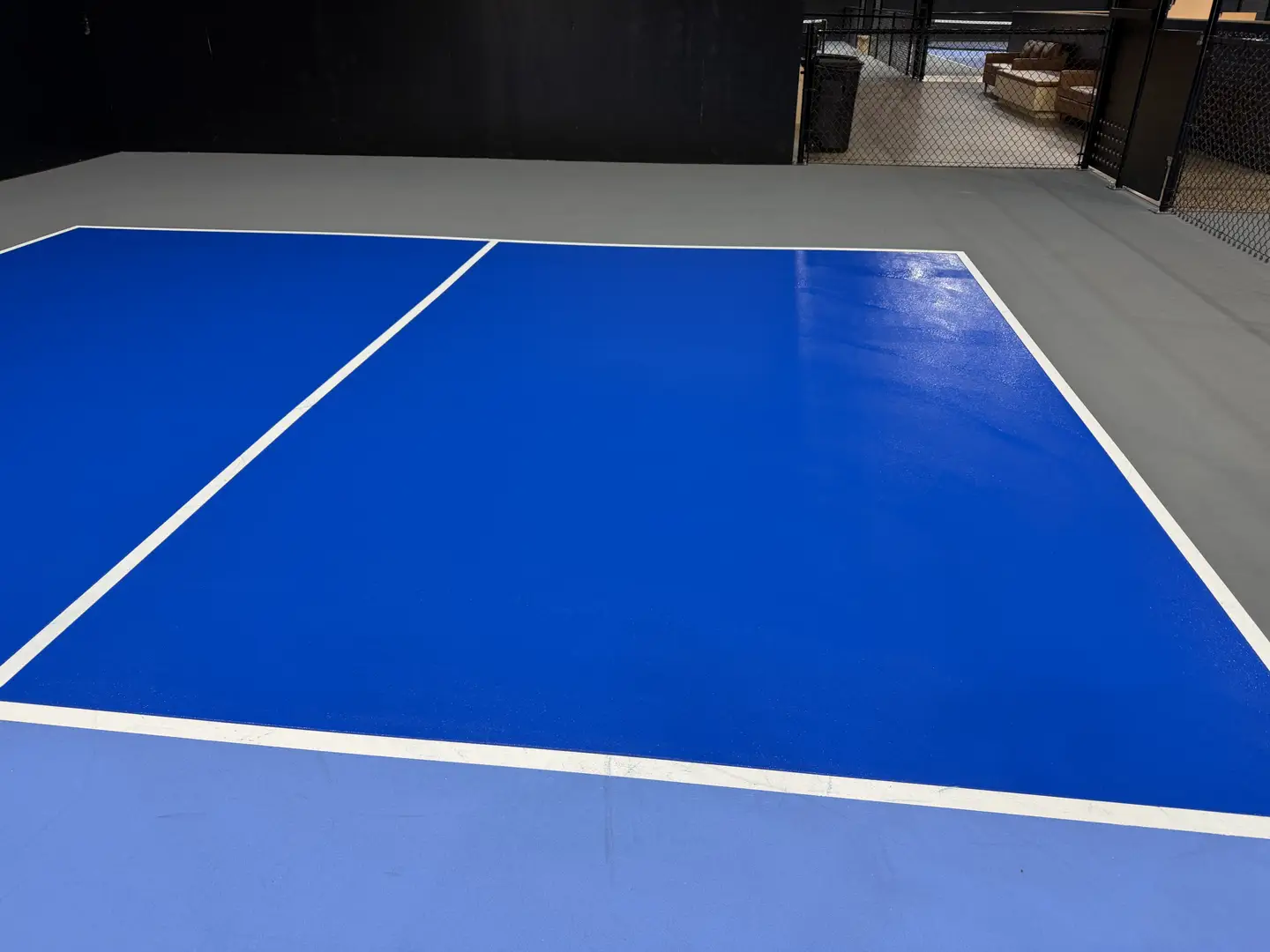 Bright blue indoor pickleball court with white lines