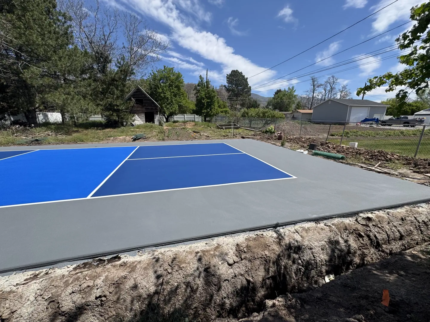 Newly painted blue and grey pickleball court with white lines.