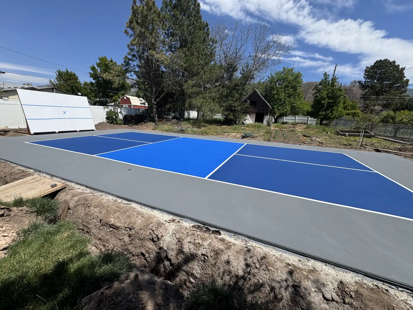 Newly painted blue and gray pickleball court with white lines.