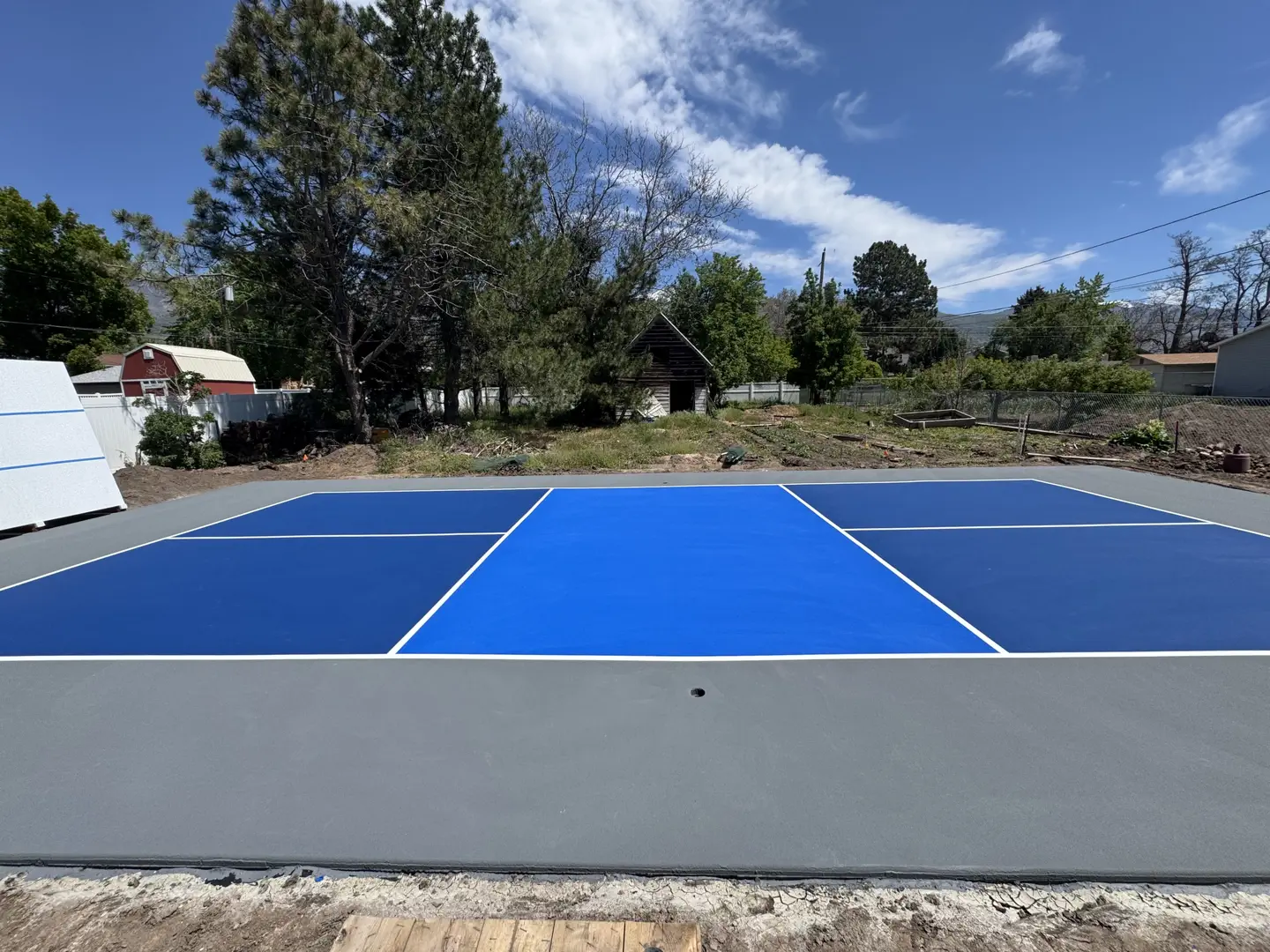 Newly painted blue and gray pickleball court with white lines.