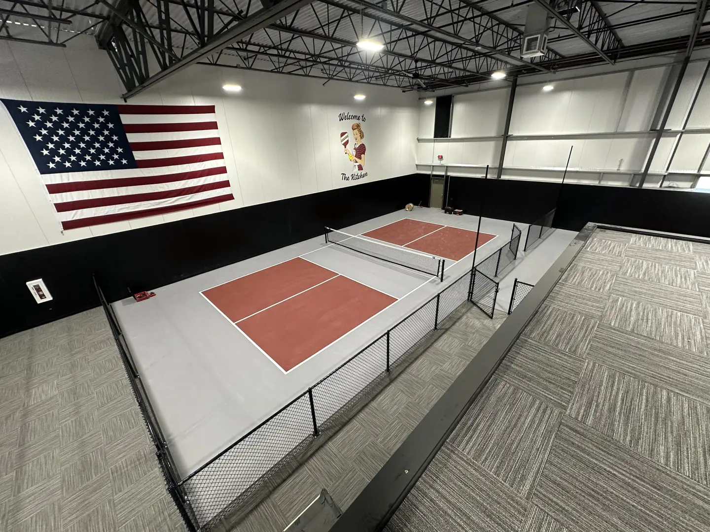 Indoor pickleball courts with American flag and 'The Kitchen' sign