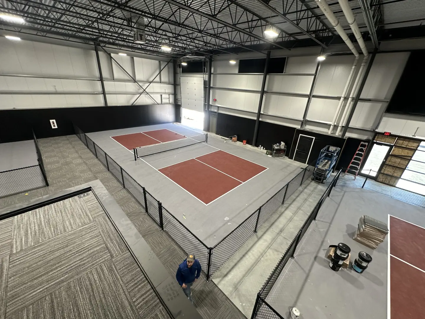 Indoor pickleball courts with red and grey surfaces and nets.