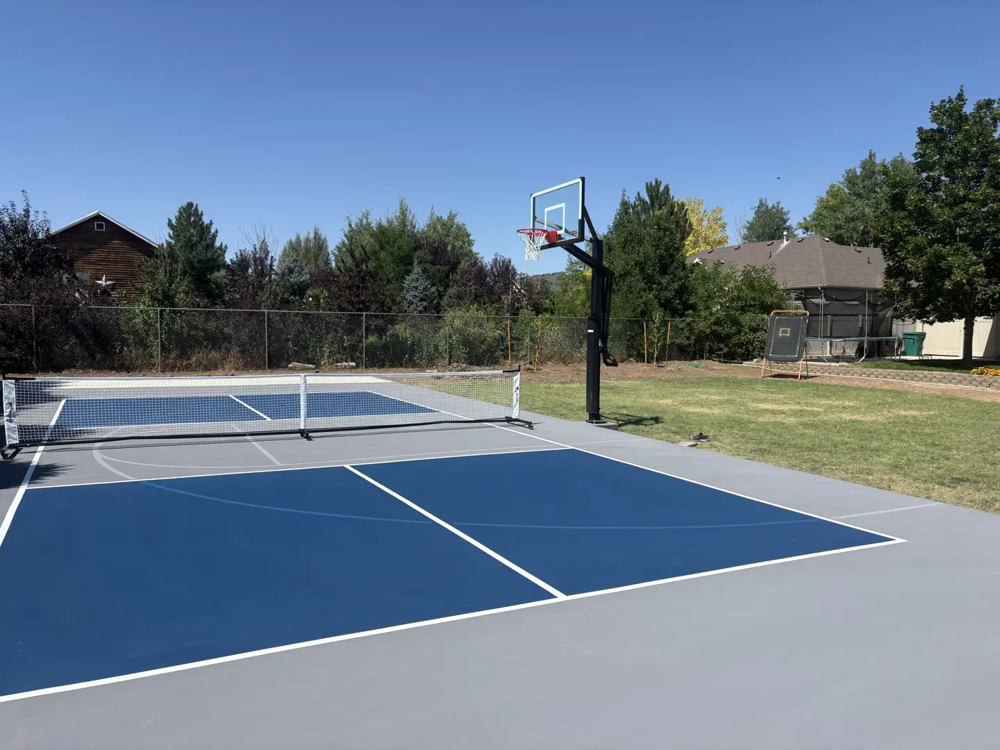 Outdoor multi-sport court with pickleball and basketball hoop.