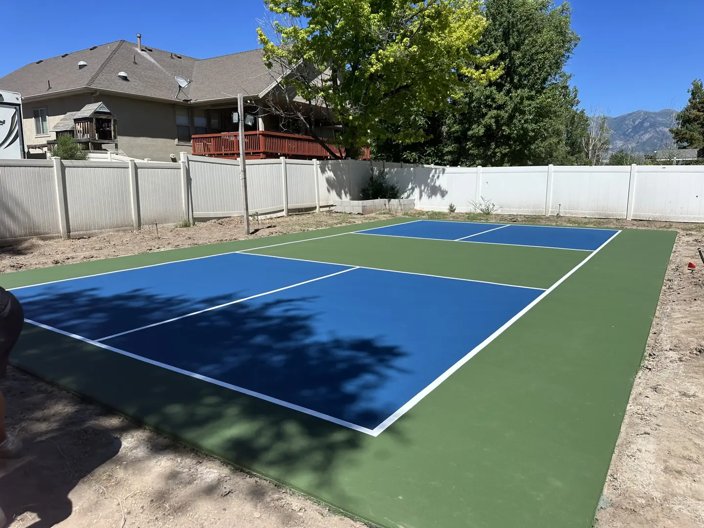 Newly painted blue and green pickleball court in a backyard.