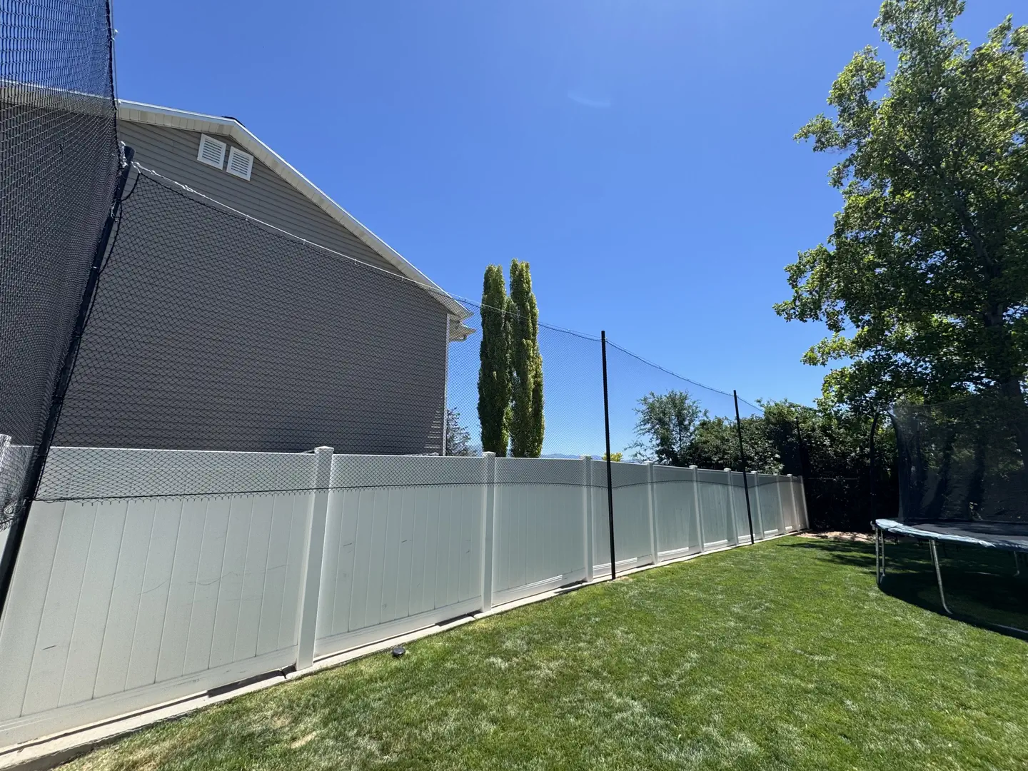 Backyard with white vinyl fence and safety netting
