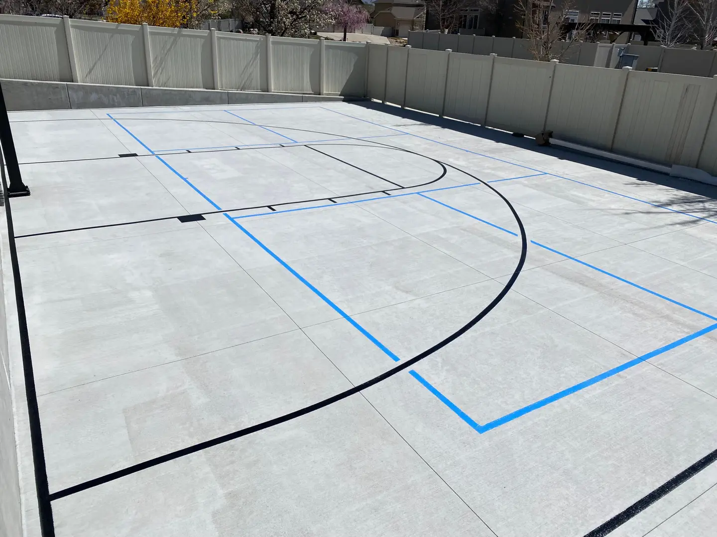 Newly painted basketball court with blue lines on a concrete surface.