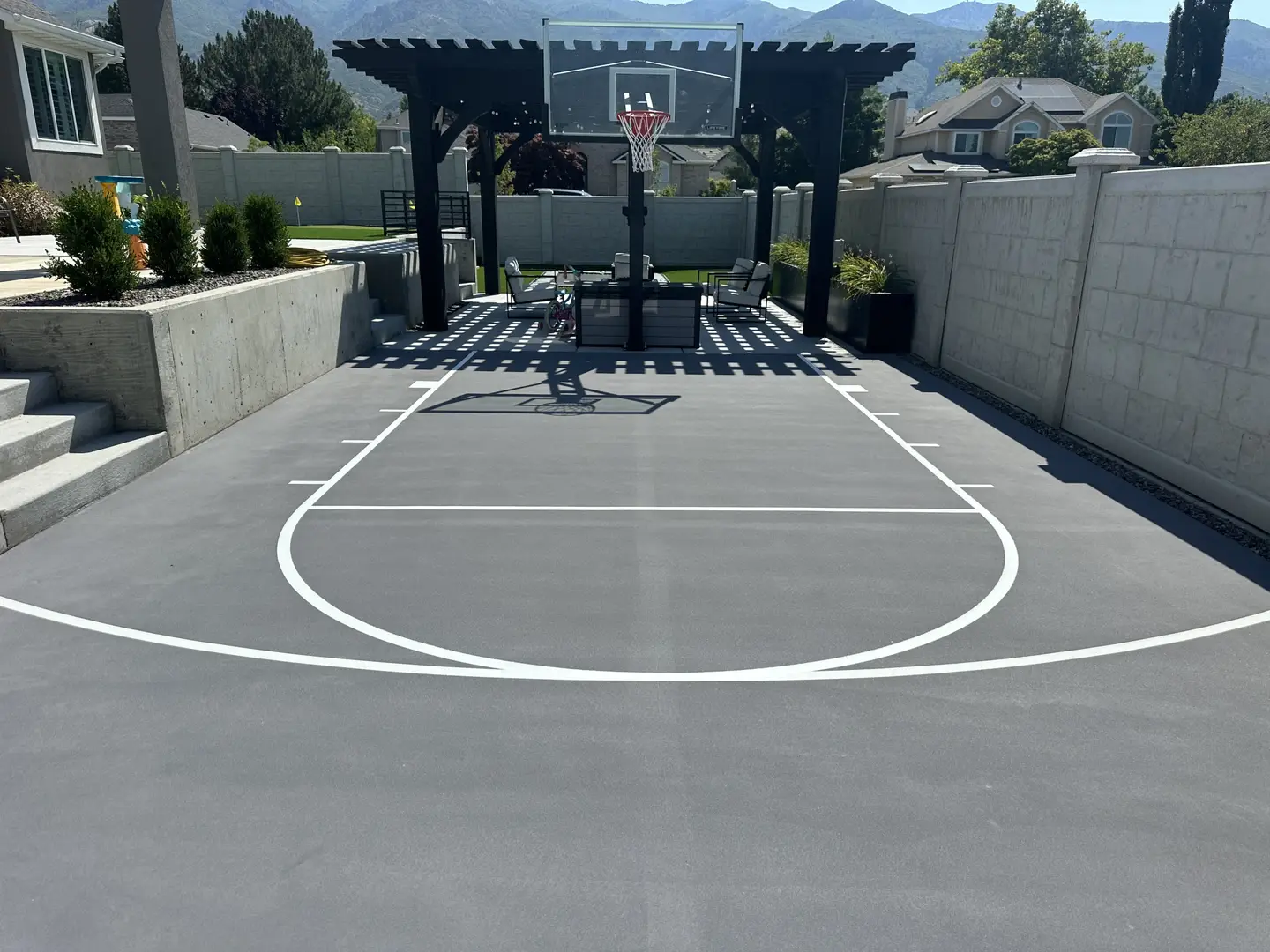 Modern backyard basketball court with pergola and mountain views.