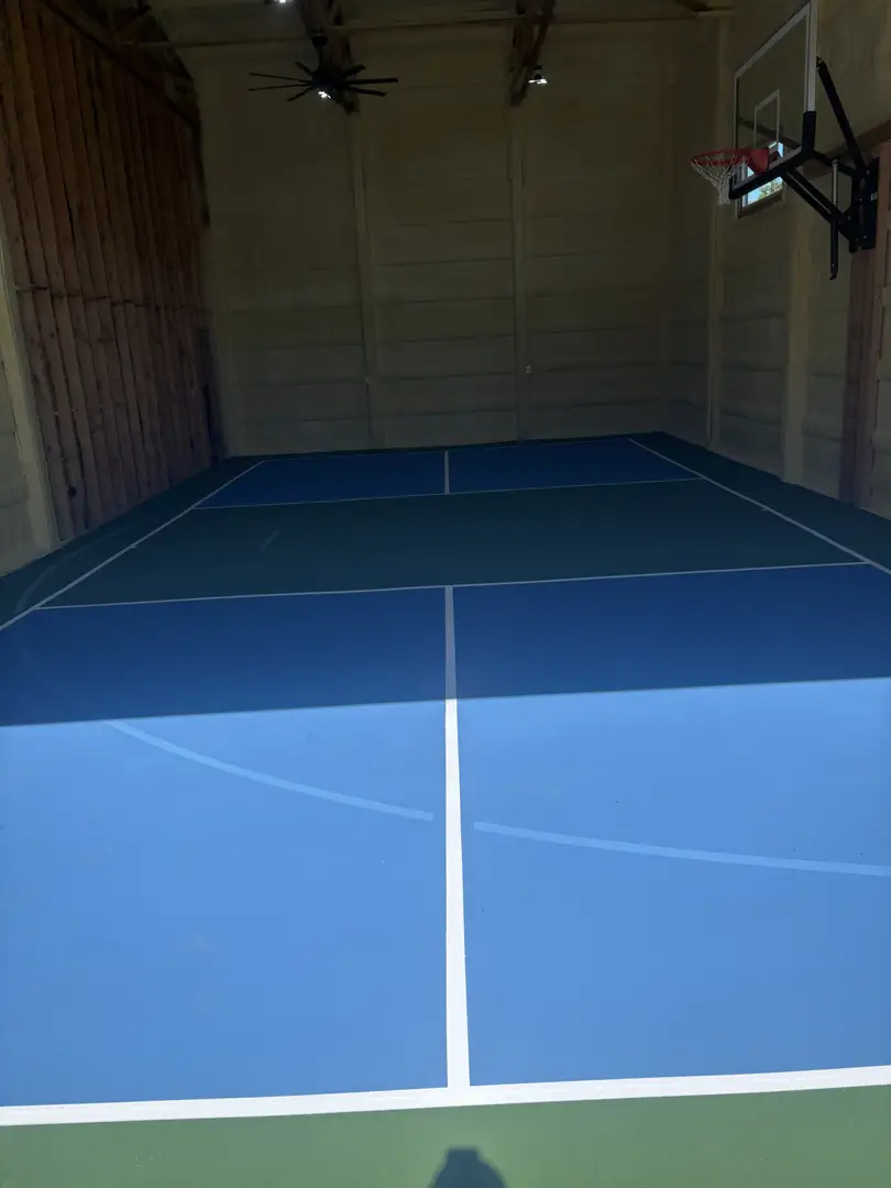 Indoor sports court with basketball hoop and tennis lines