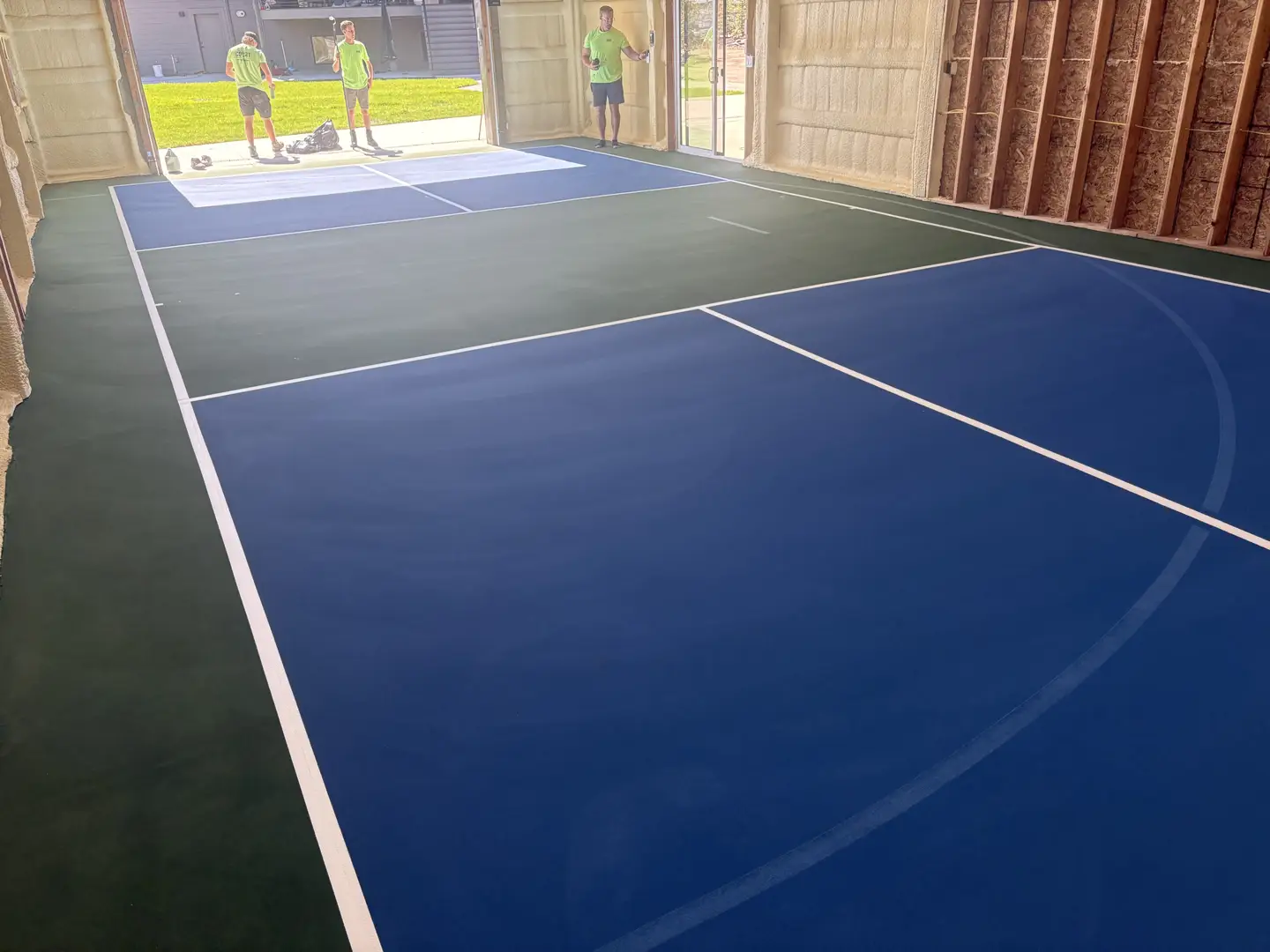 Newly painted indoor pickleball court in blue and green.