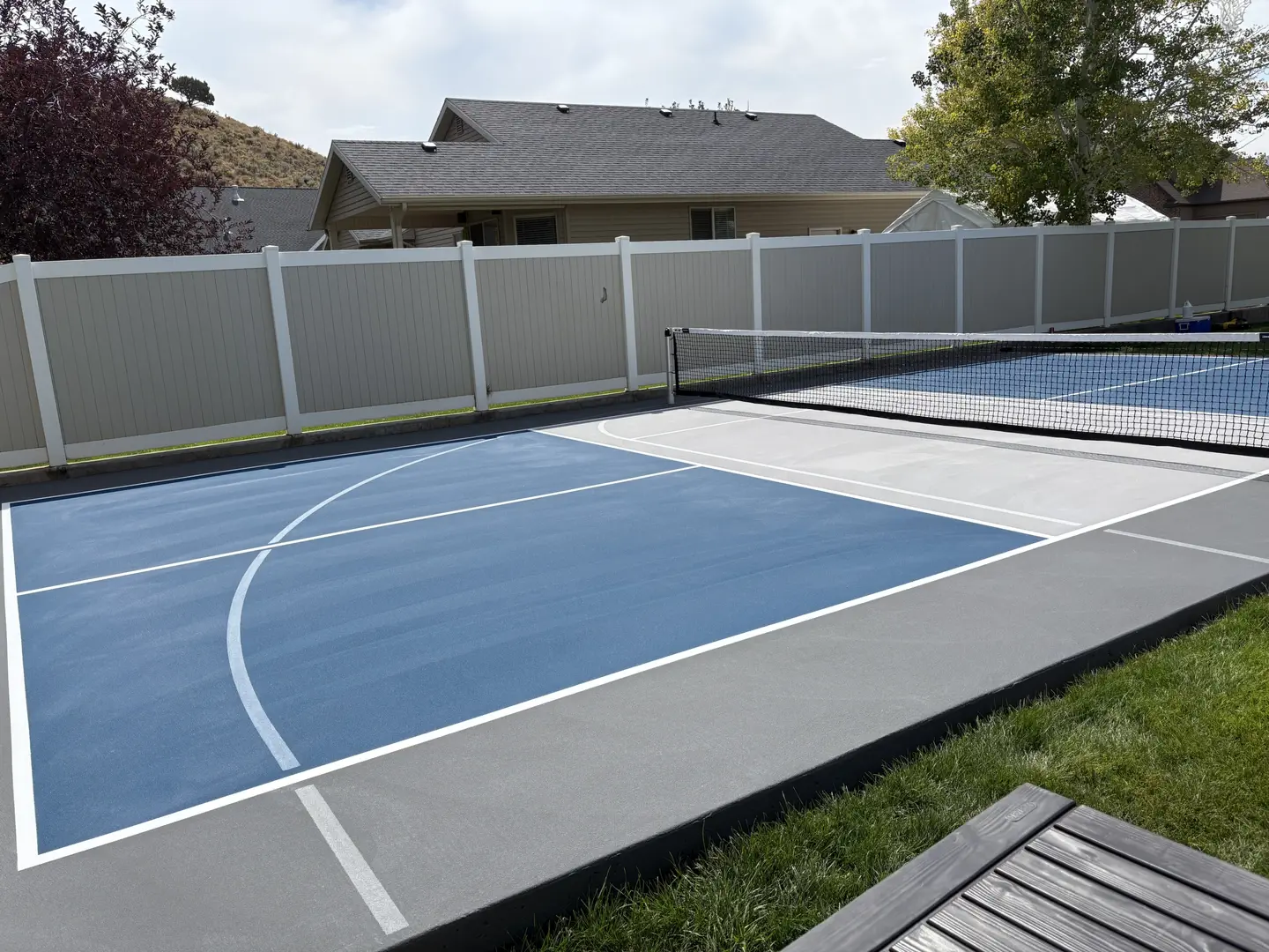 Blue and grey pickleball court with net and fence