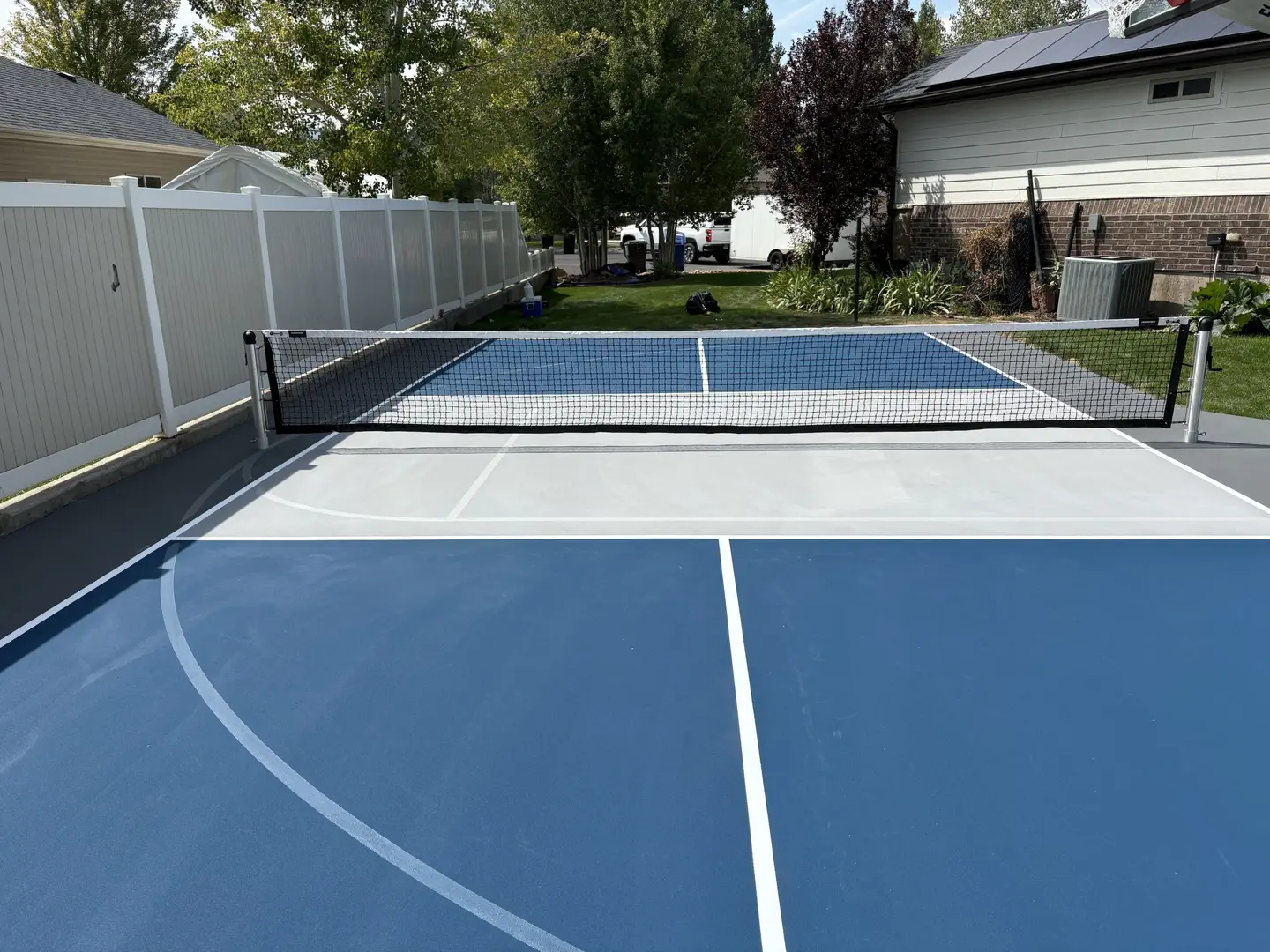 Newly painted blue and gray pickleball court with net.