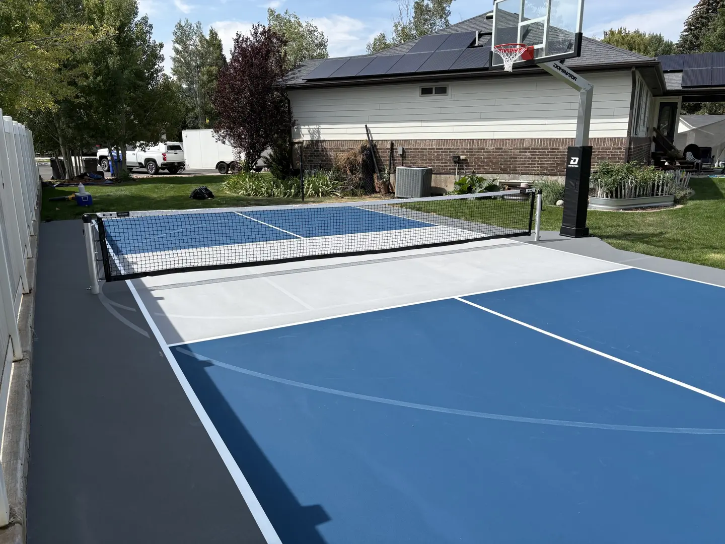 Newly painted blue and grey pickleball court with basketball hoop