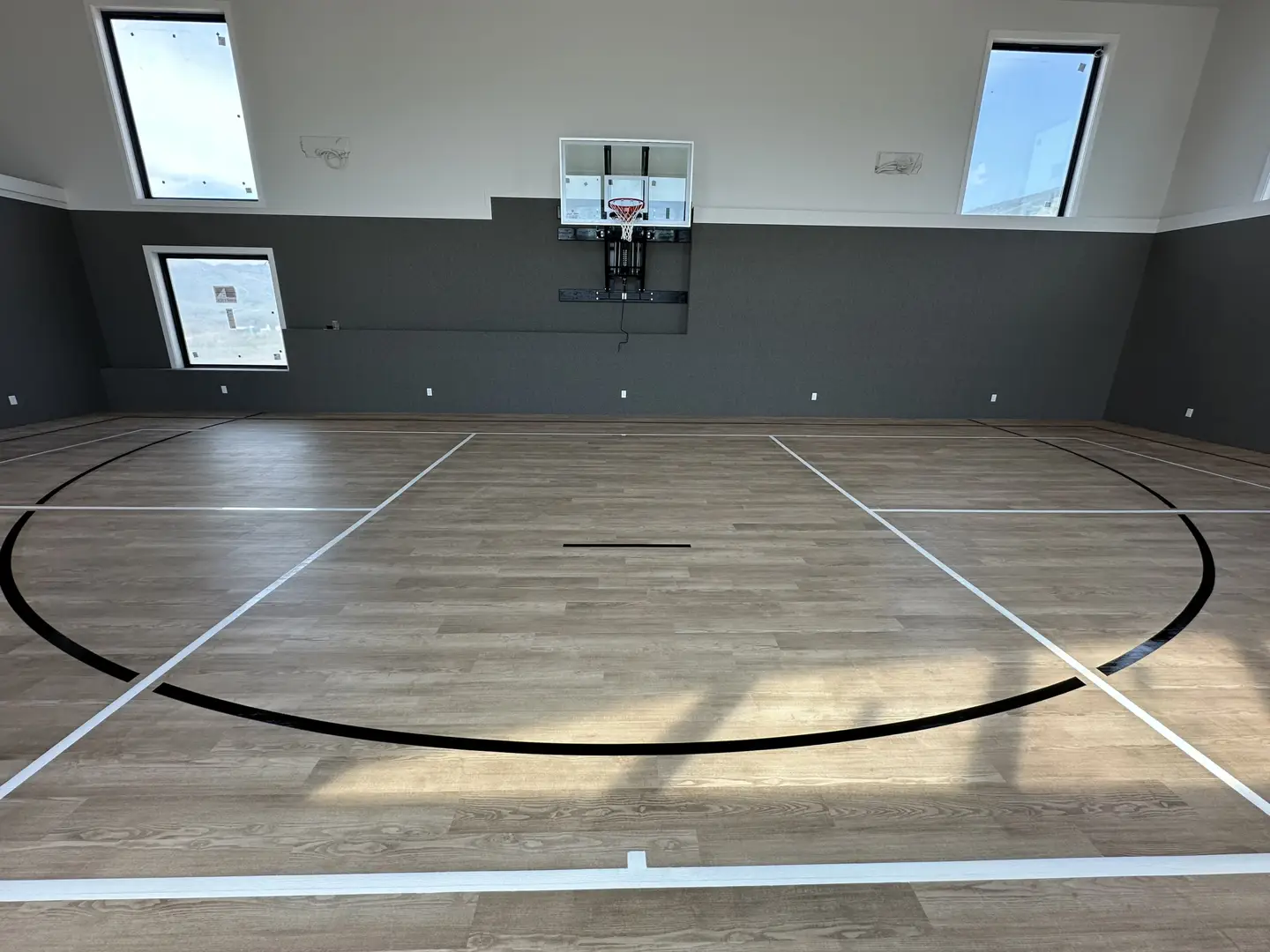 Indoor basketball court with wood-look flooring and skylights.