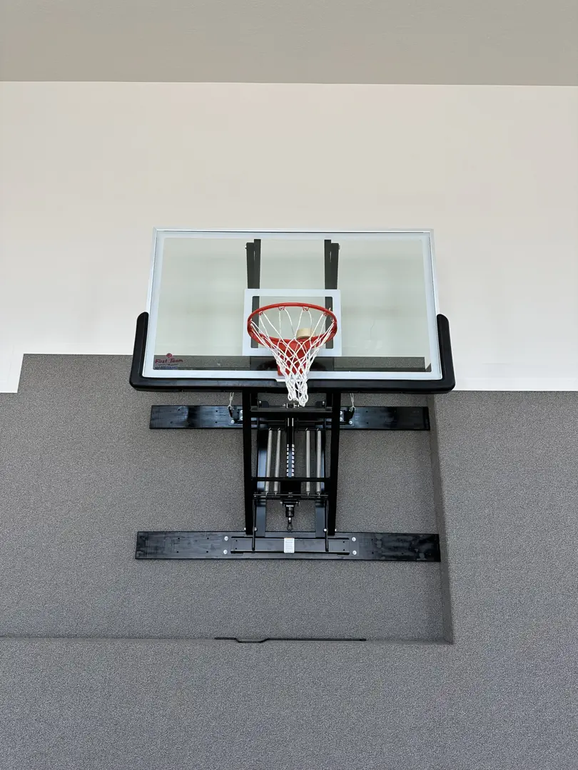 Adjustable height basketball hoop with glass backboard mounted on a wall