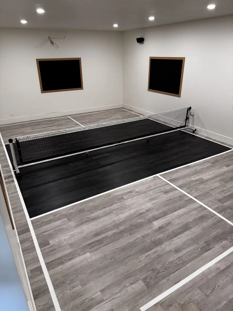 Indoor pickleball court with a net and blackboards on the wall.