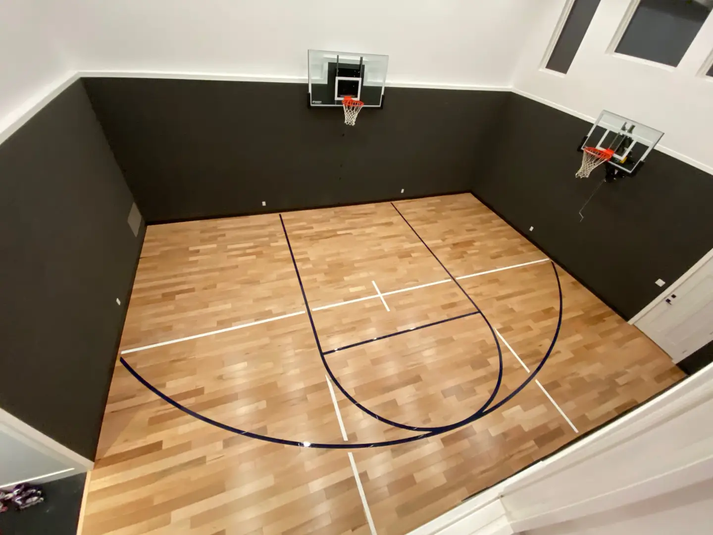 Indoor basketball court with hardwood floor and two hoops.