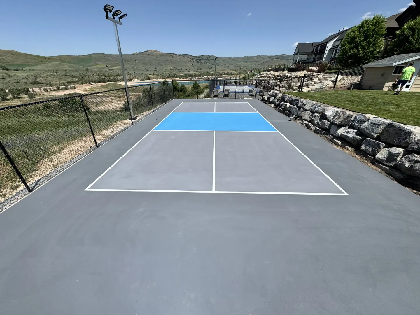 Outdoor pickleball court with blue accent and mountain view