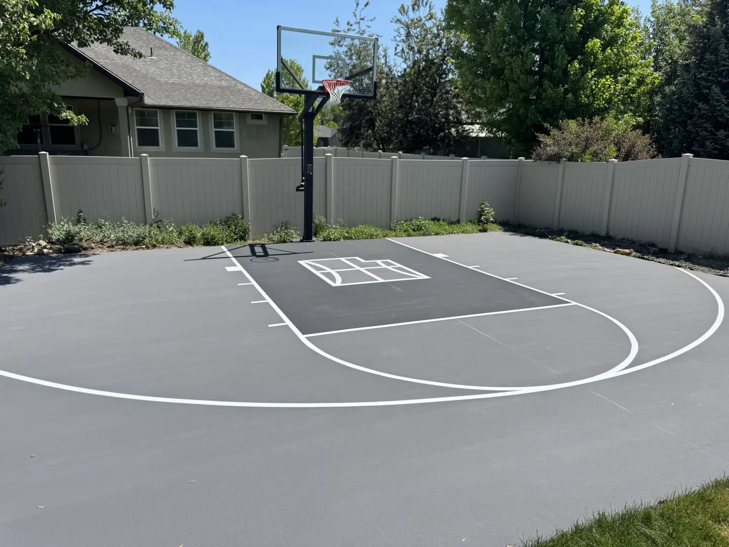 Newly painted backyard basketball court with a hoop and white lines.