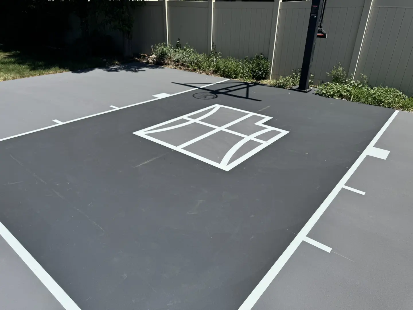 Newly painted basketball court with a stylized basketball logo in the center.