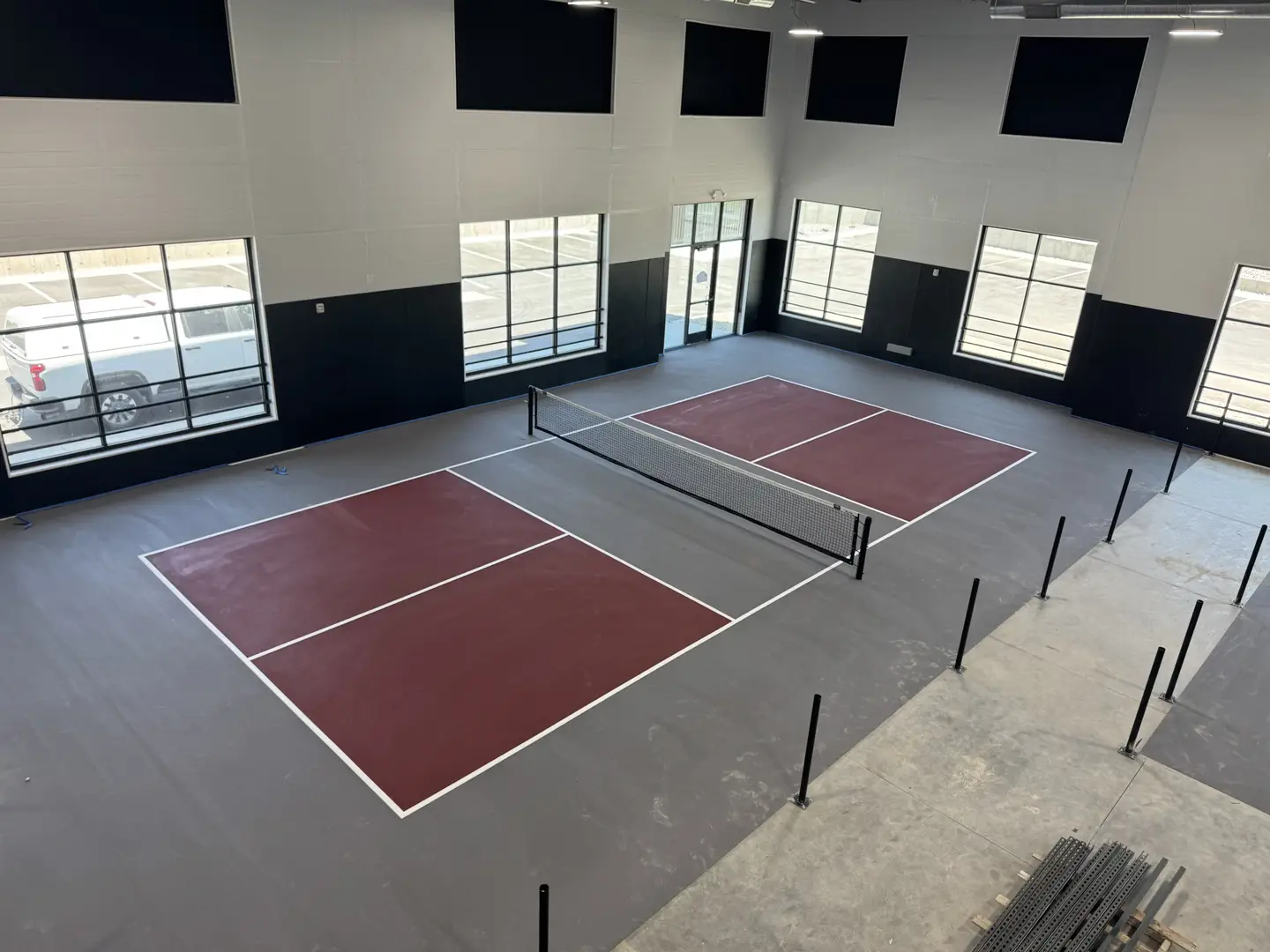 Indoor pickleball courts with maroon and gray surfaces.