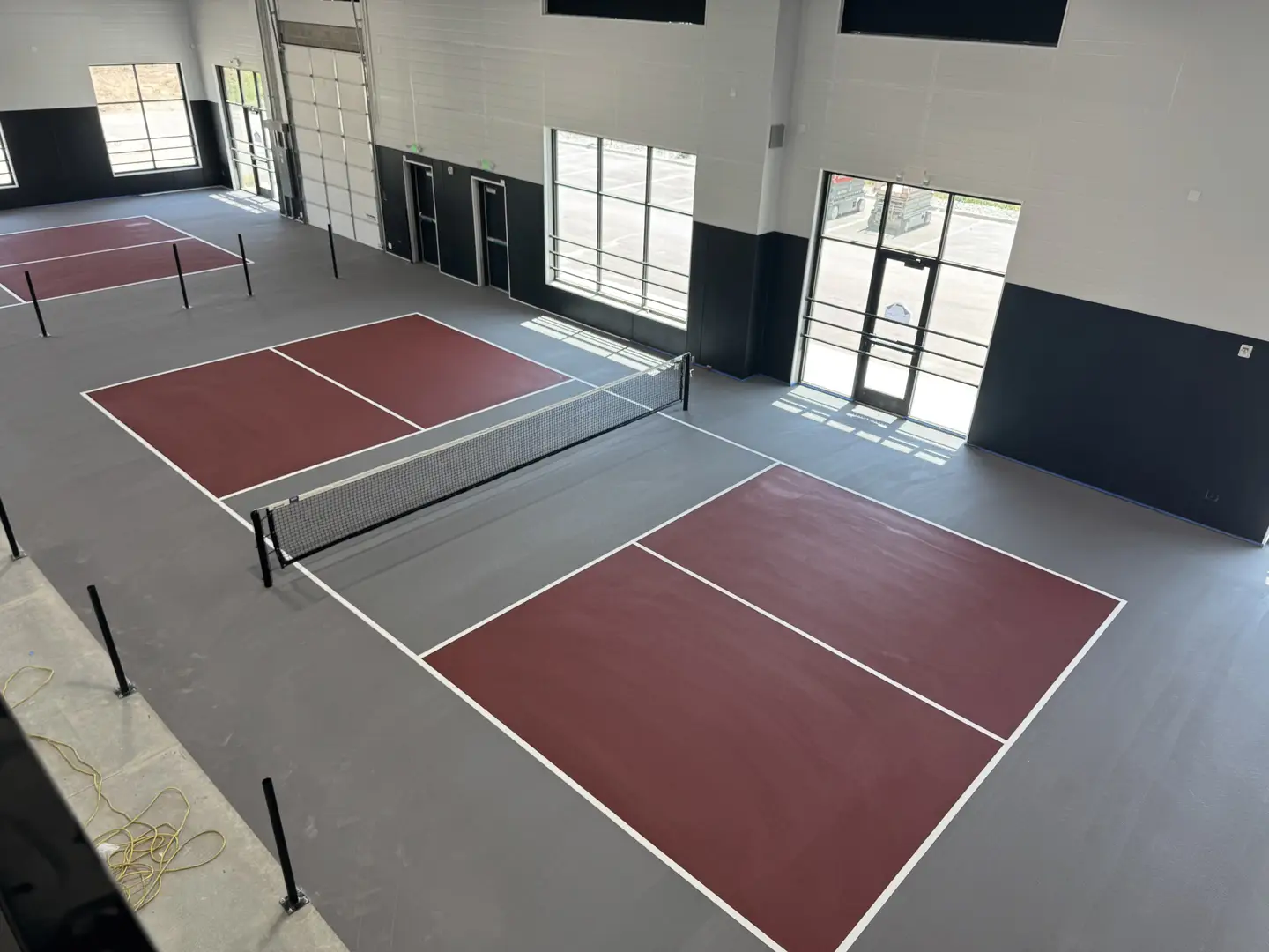 Indoor pickleball courts with maroon playing surfaces and gray surrounds.