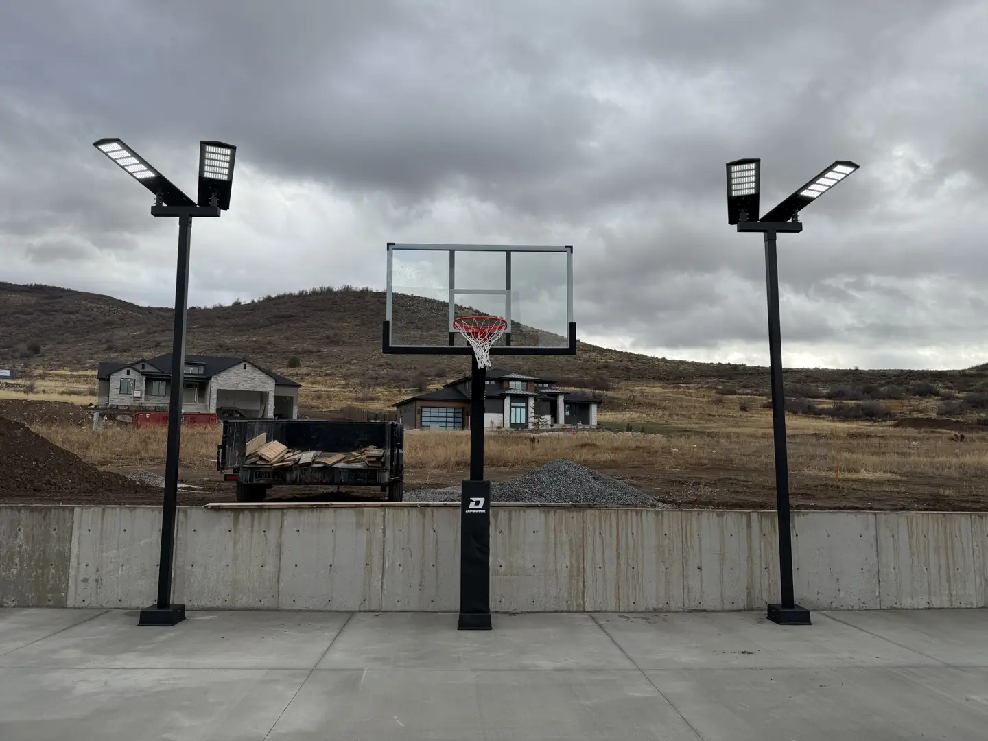 Basketball hoop with dual LED lights and residential homes in background.