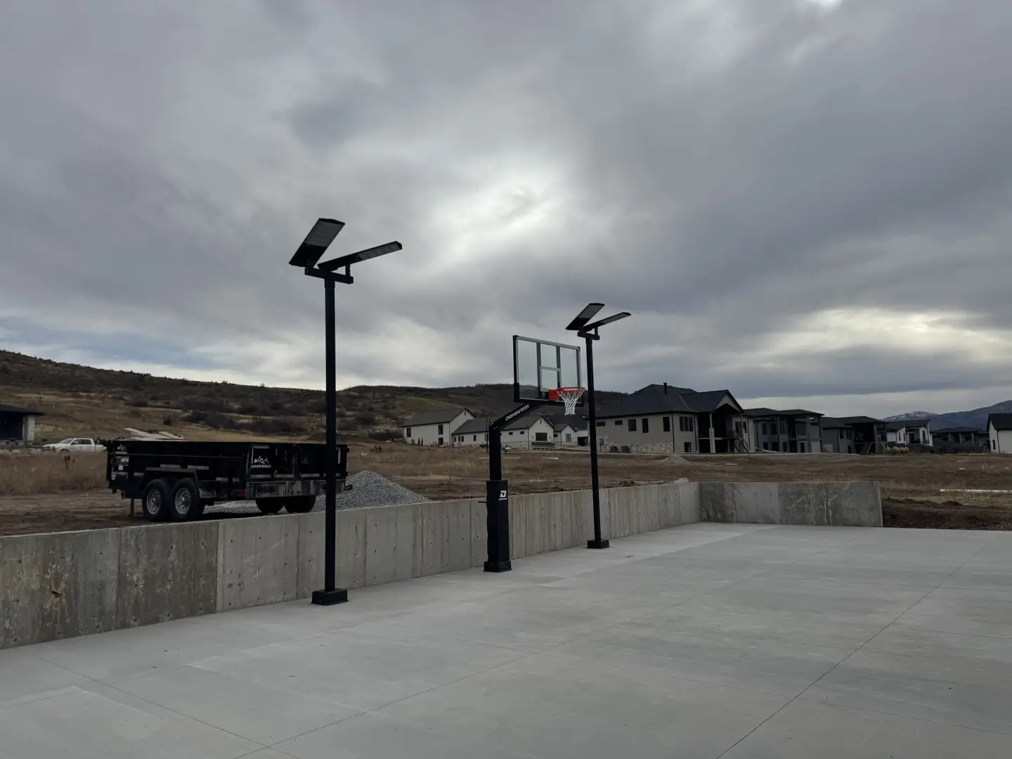 Basketball court with lights and hoop, construction site in background.
