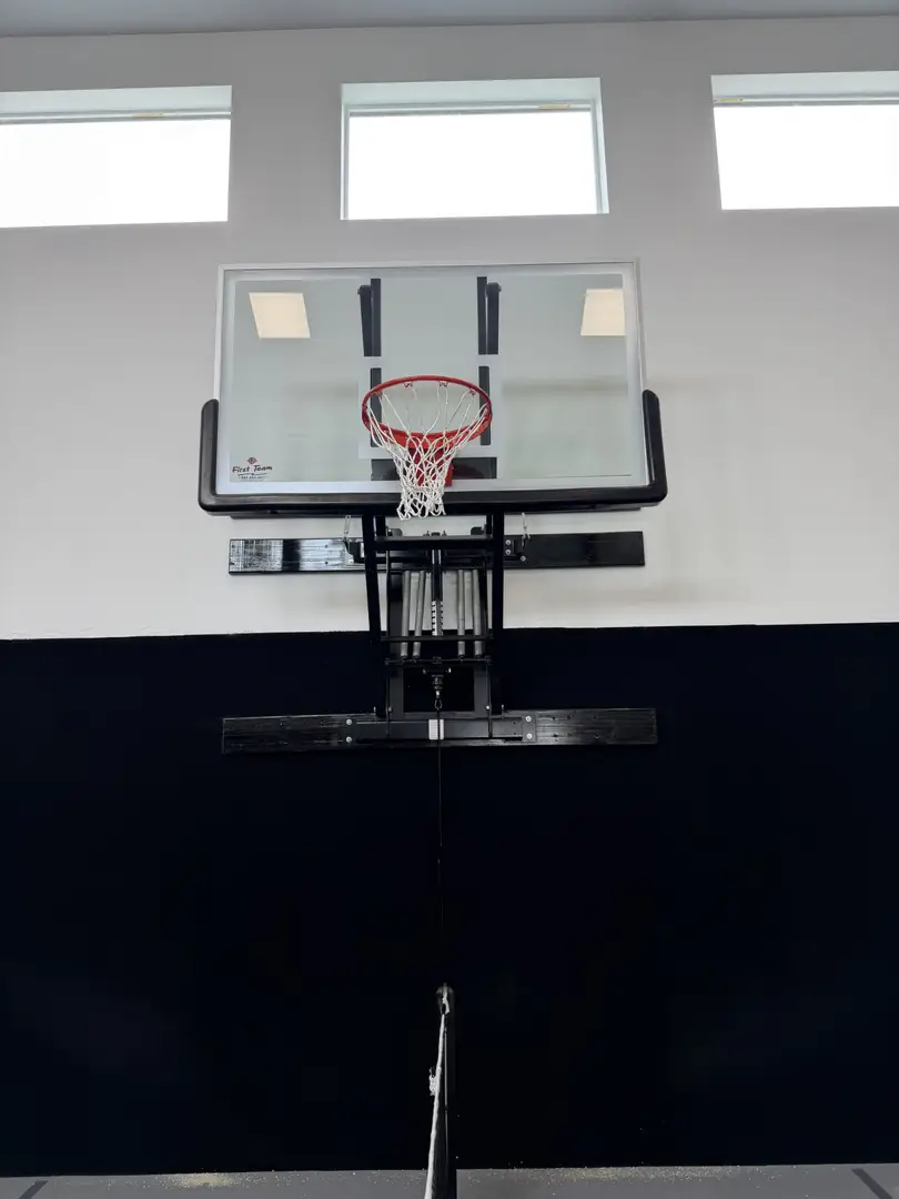 Adjustable basketball hoop mounted indoors