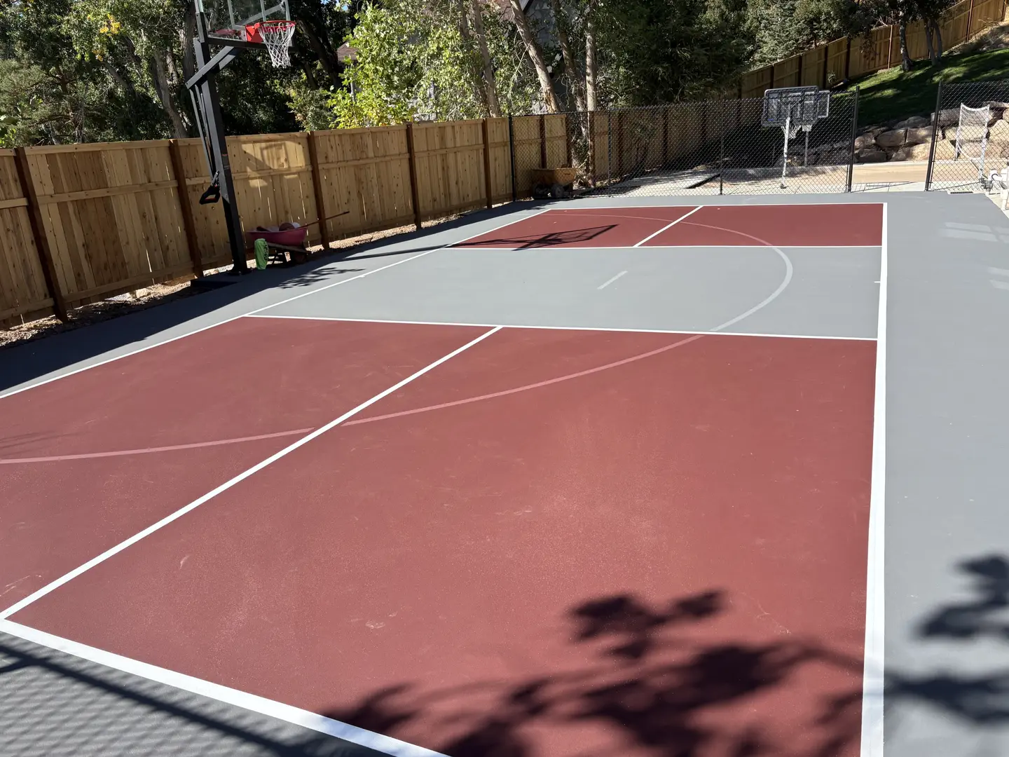 Newly installed red and grey basketball court with white lines.