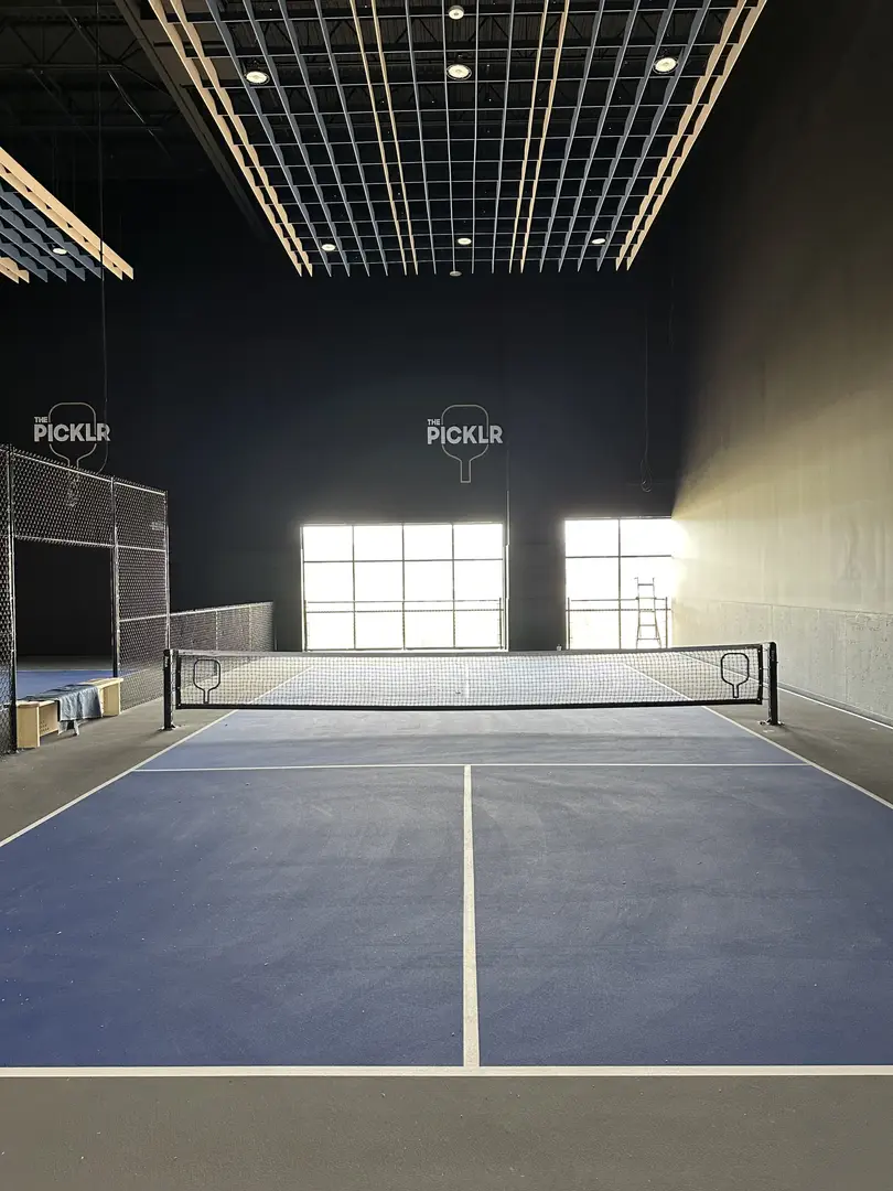 Indoor pickleball court at The Picklr with blue surface and net.