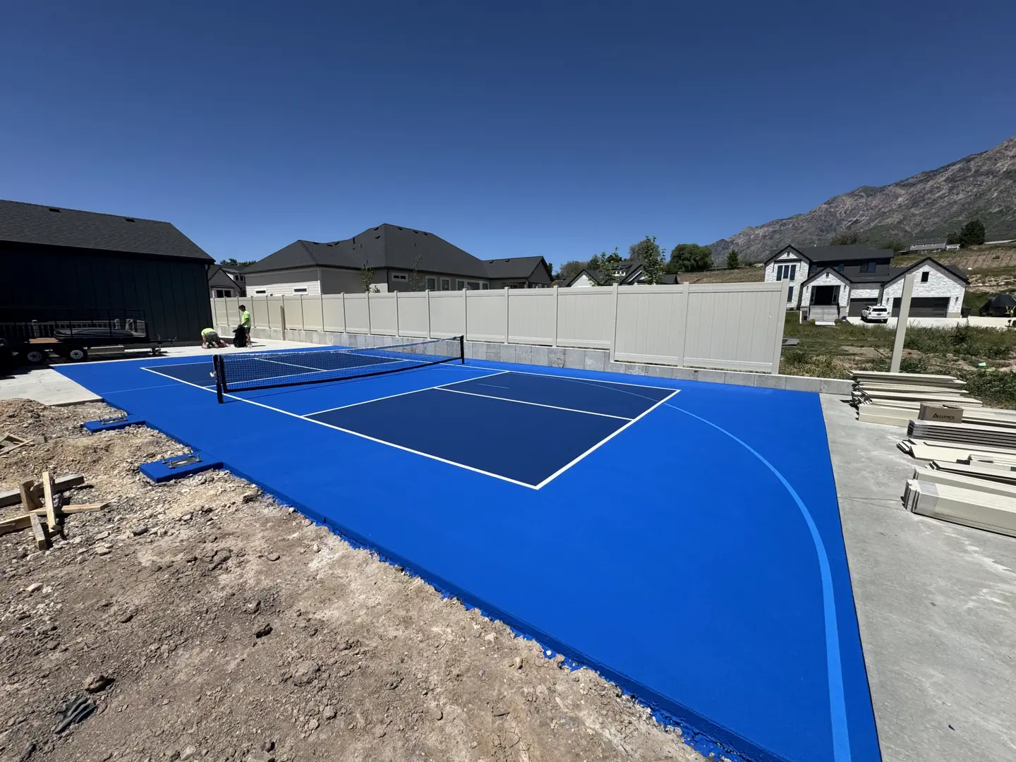 Newly painted blue pickleball court with white lines and net.