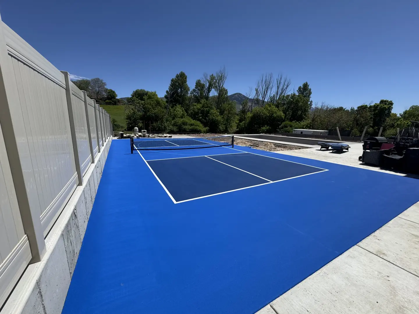 Vibrant blue pickleball court with white lines and a net.