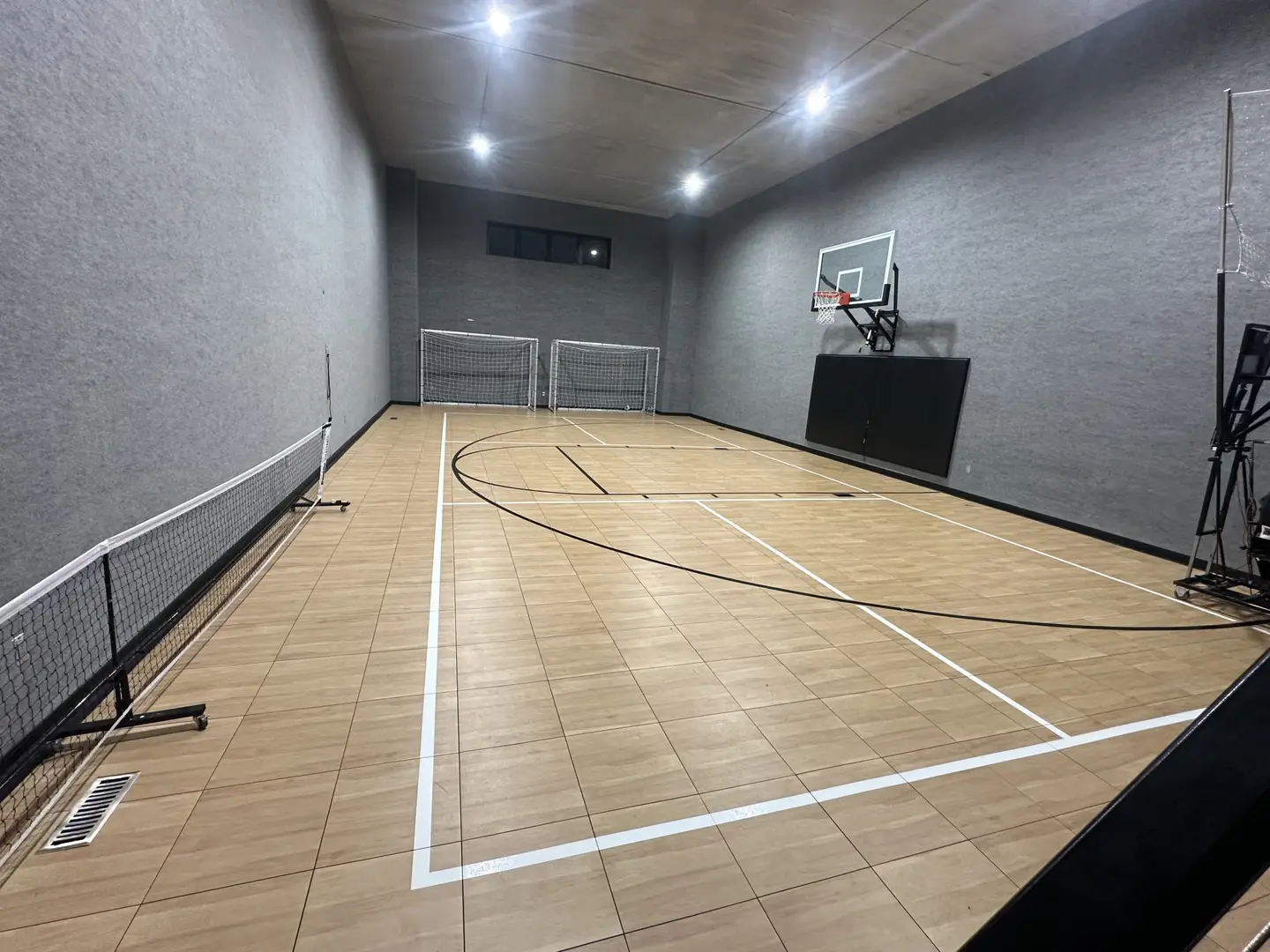 Indoor multi-sport court with basketball hoop and soccer goals