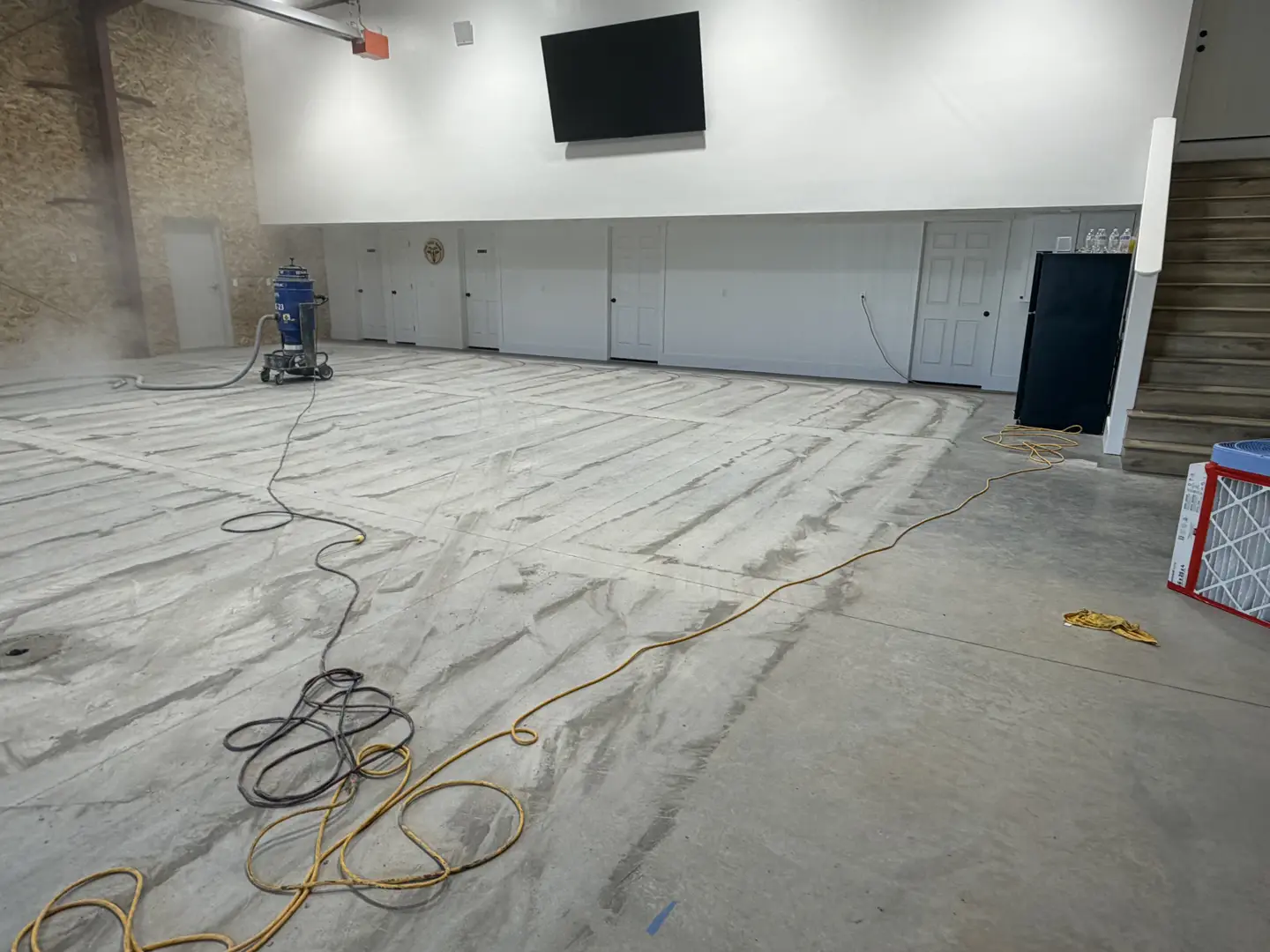 Concrete floor grinding and dust collection in progress.
