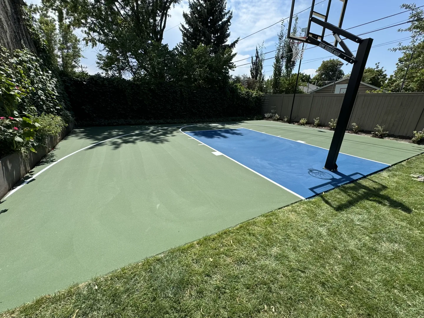 Backyard basketball court with green and blue playing surface