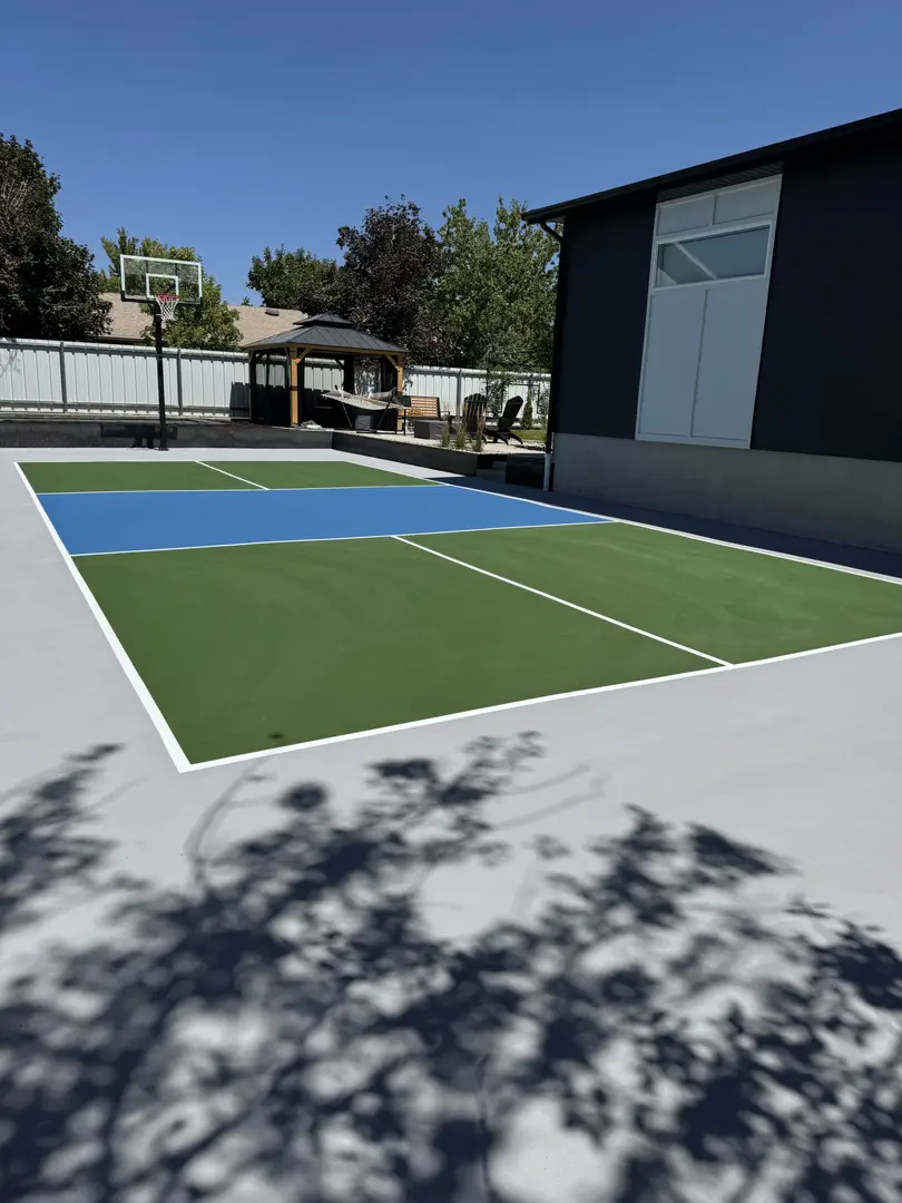 Multi-sport court with green and blue sections, basketball hoop in background.