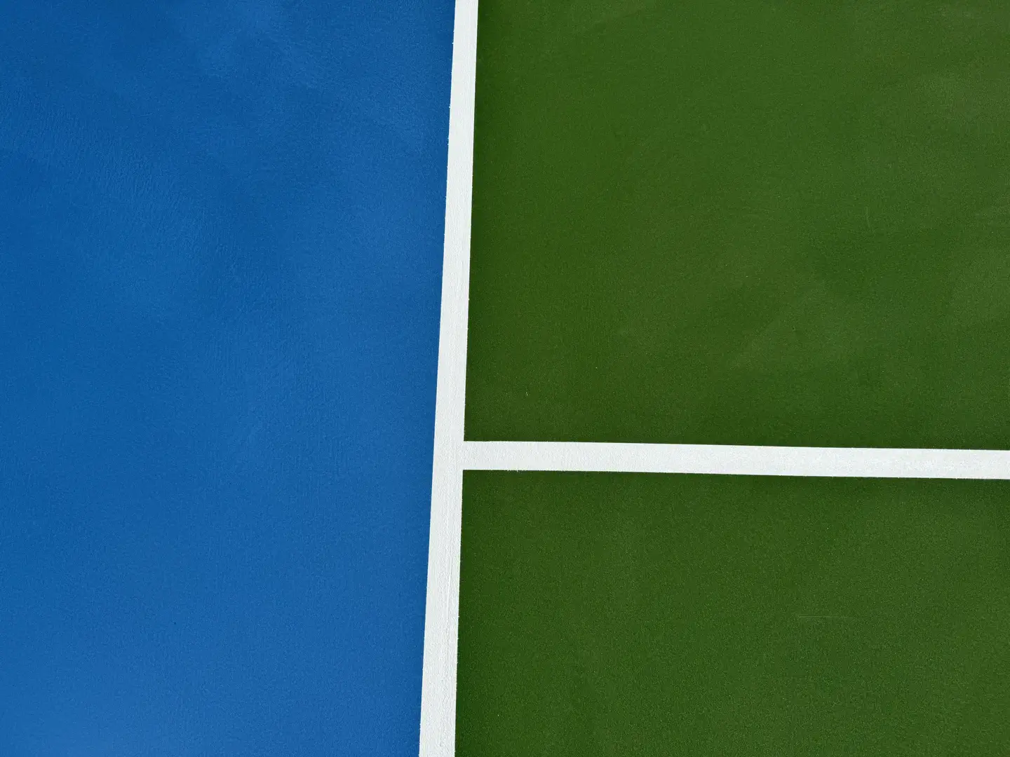 Close-up of a blue and green tennis court with white lines.