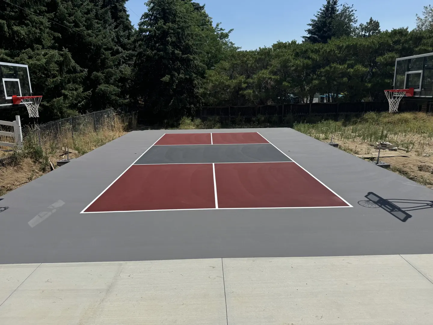 Newly painted basketball court with red and grey sections.