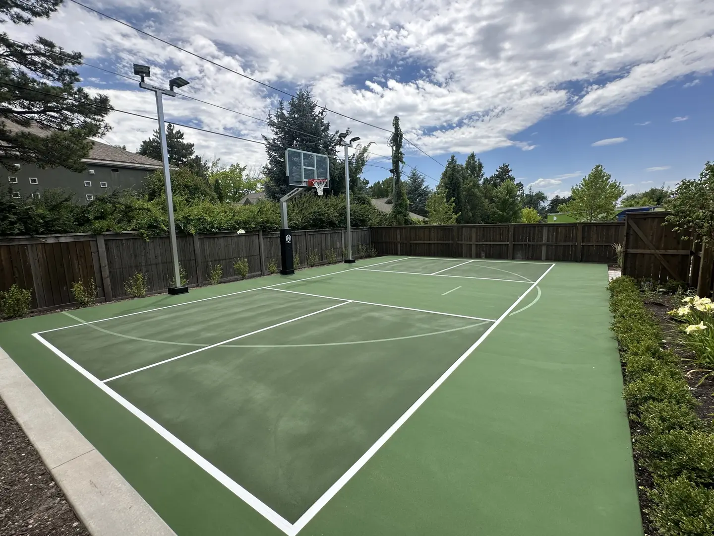 Backyard basketball court with lighting and wooden fence