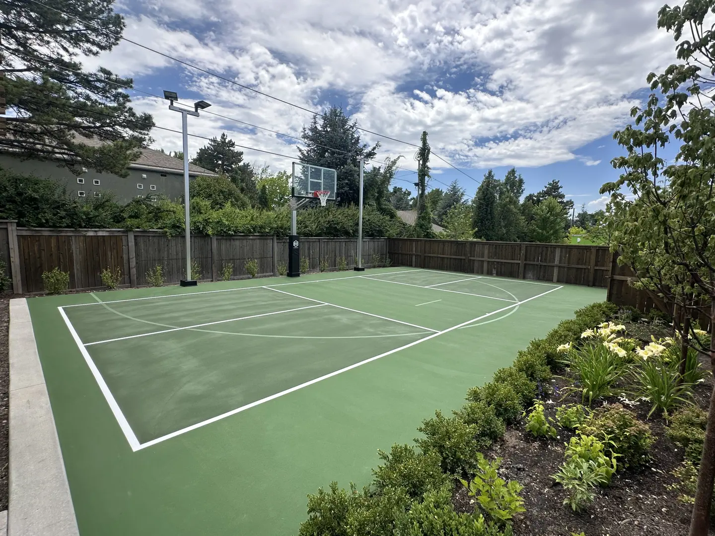 Backyard basketball court with green surface and white lines.