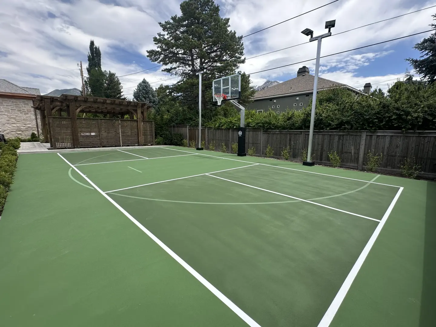 Green backyard basketball court with lighting