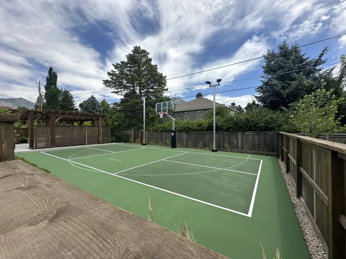 Backyard basketball court with green surface and white lines.
