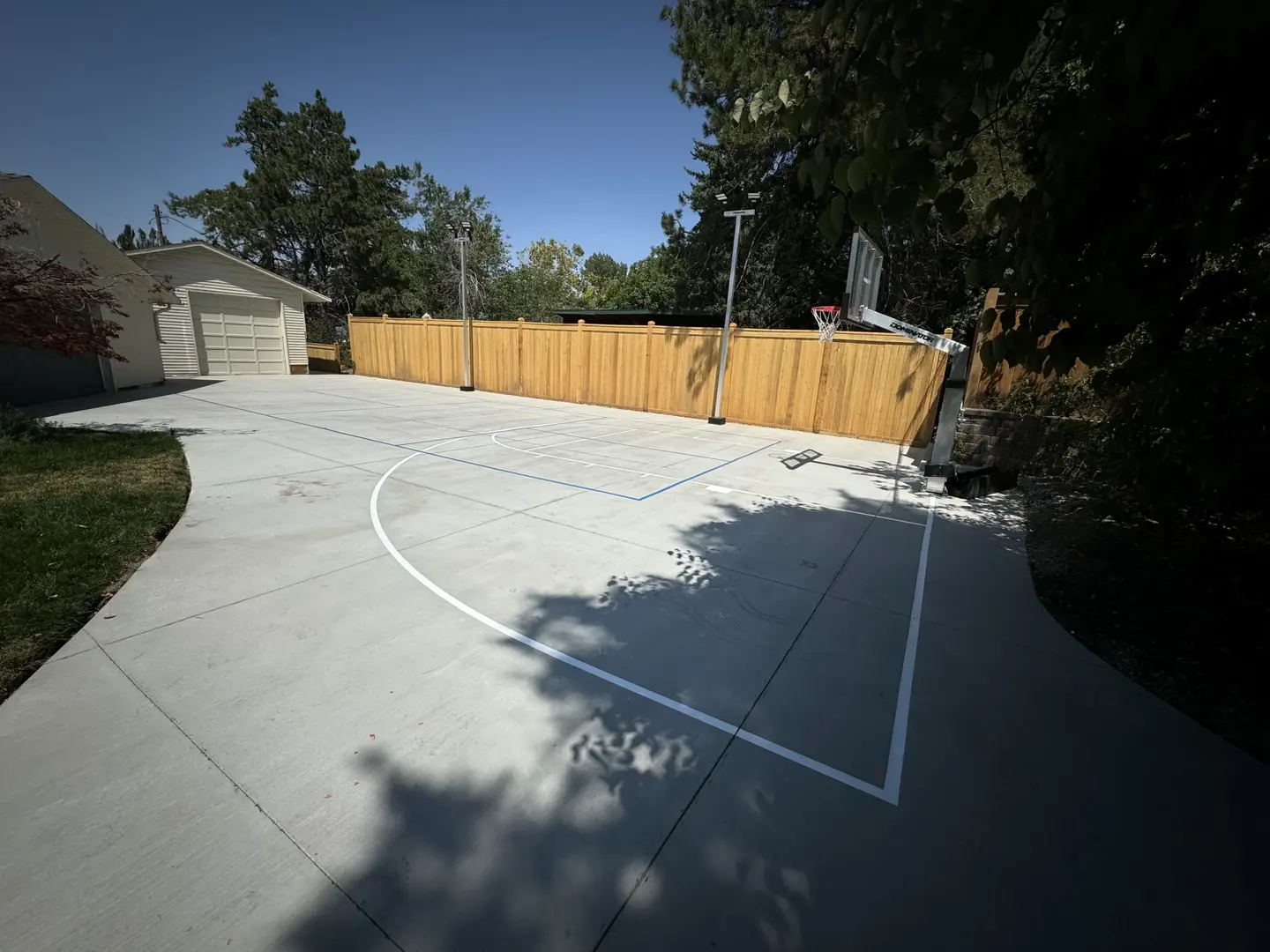 New concrete basketball court with wooden fence and hoop