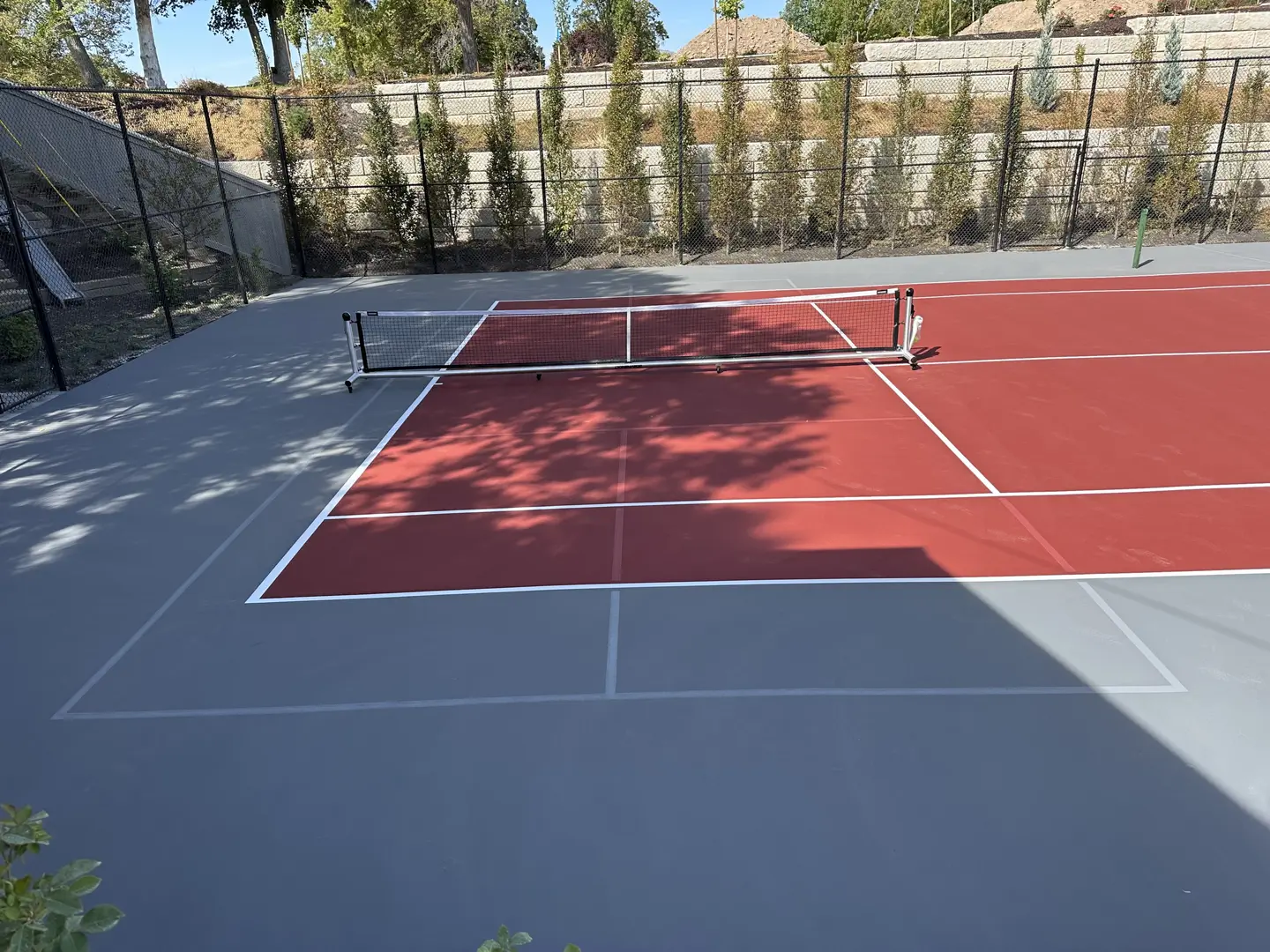 Red and gray tennis court with net and fence