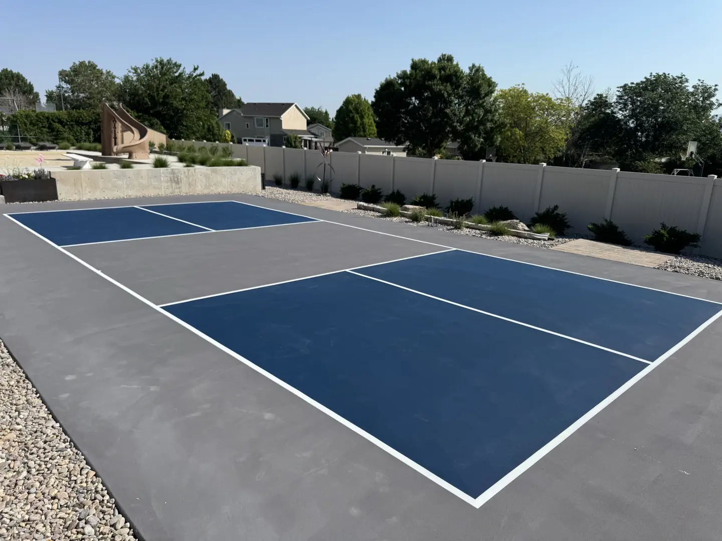 Newly painted pickleball court with blue and gray surfaces.