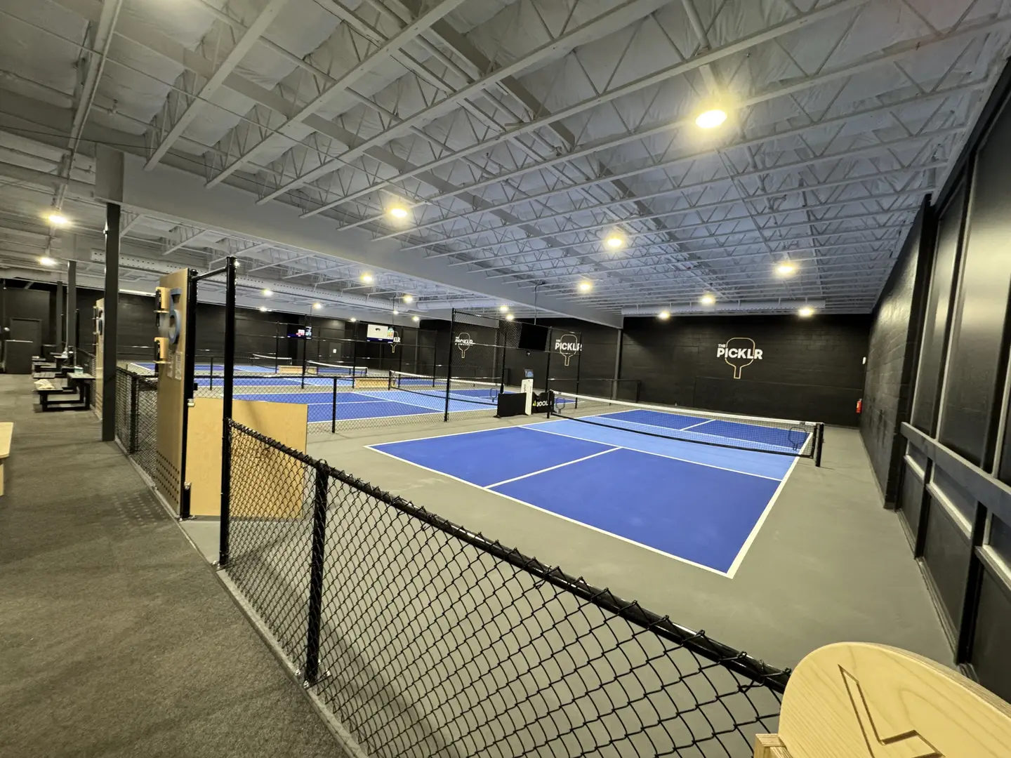 Indoor pickleball courts at The Picklr with blue playing surfaces.