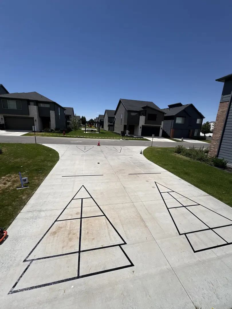 Outdoor shuffleboard court painted on a driveway with modern homes in the background.