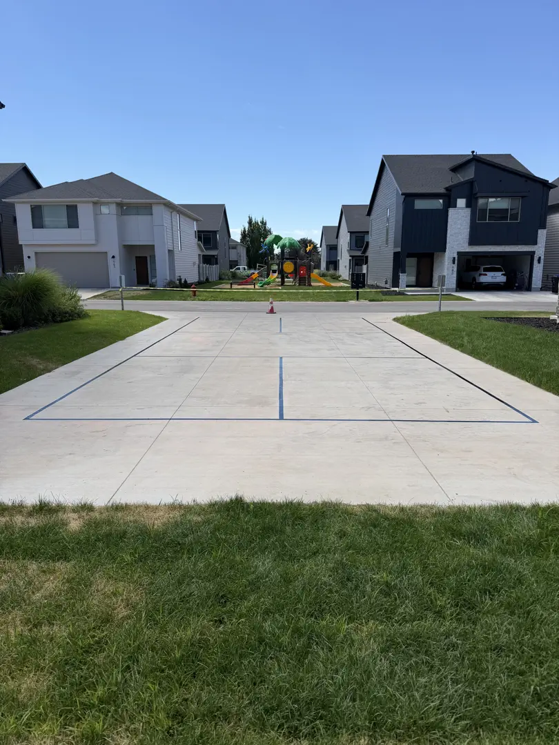 Concrete court with lines for games, residential neighborhood with houses and playground