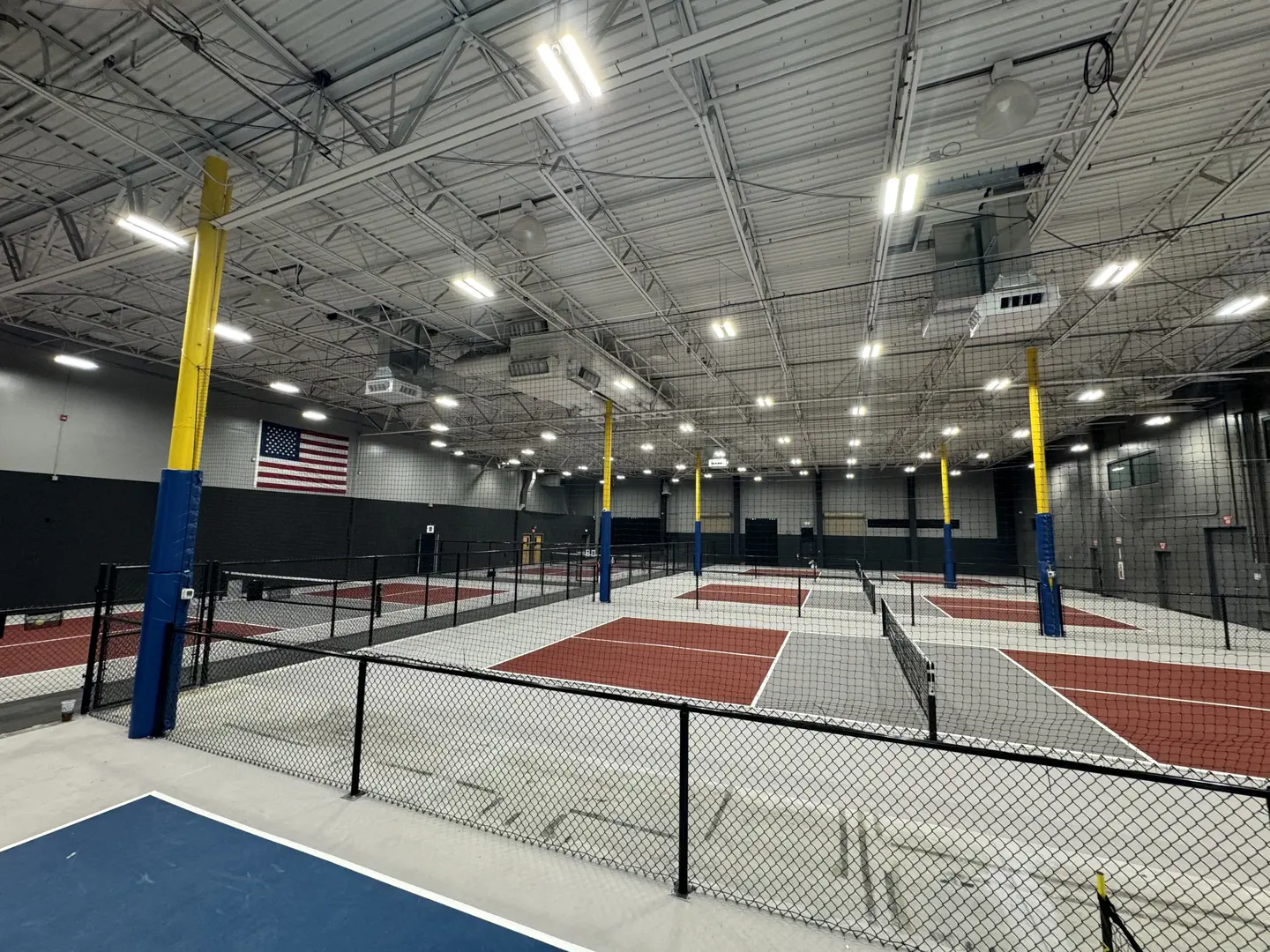Indoor pickleball courts with nets and bright lighting.